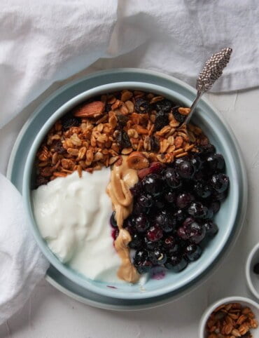 Domowa granola bg, jogurt roślinny, pasta orzechowa i borówki na ciepło